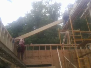 Carpenter raising a rafter beam on a new second story frame in Lexington