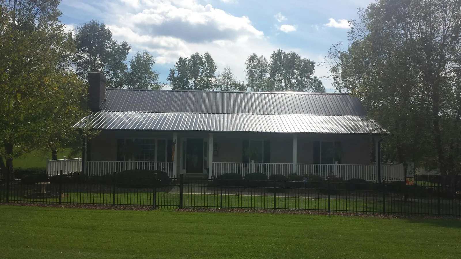 Gray metal roof on a brick ranch with a full width front porch — Gutter Guard Installation work by our crew in Lexington